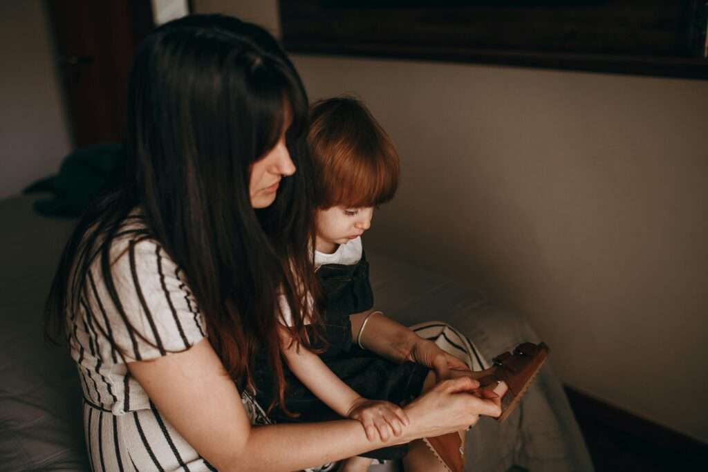A mother teaching her young daughter while seated indoors. A tender moment of learning and connection.