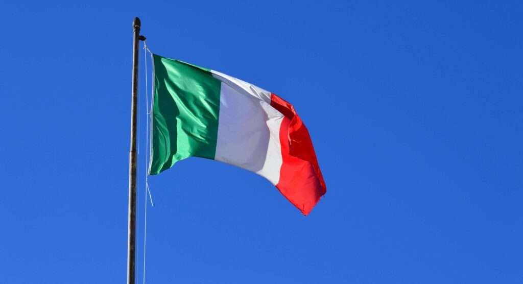 Italian flag flying against a vibrant blue sky, symbolizing national pride and identity.